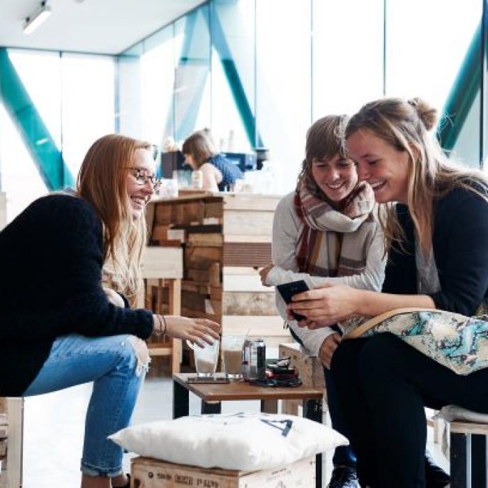 pictures of 3 students discussing with their phones in their hands