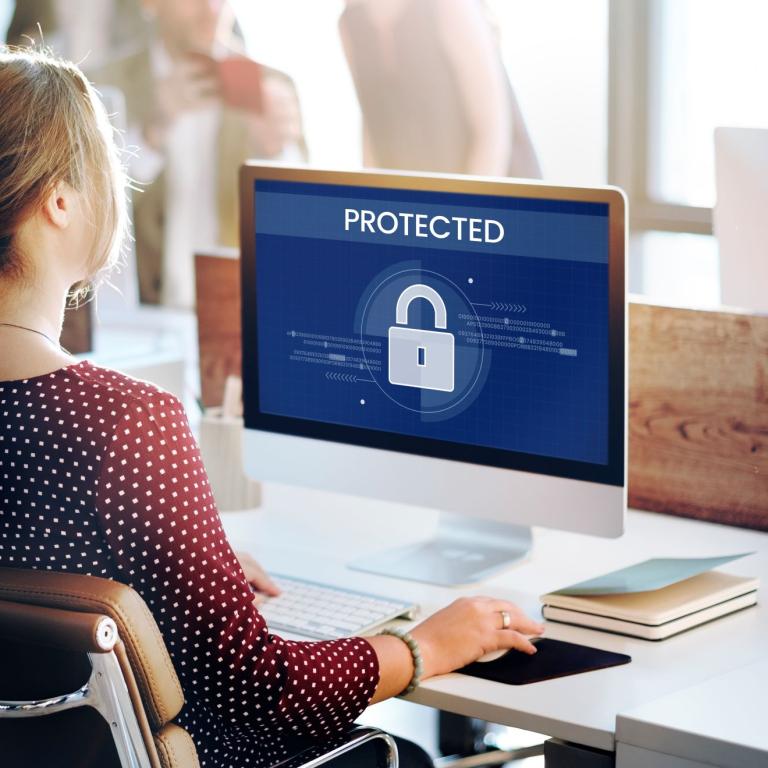 woman working at a computer with a padlock symbolising security on the screen